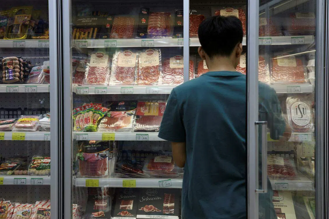 A staff member stocks a freezer where pork and other meat products are displayed, at a supermarket in Beijing, China June 13, 2024. REUTERS/Florence Lo