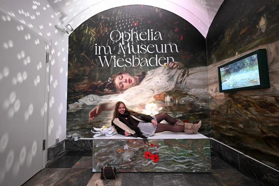 A fan of Taylor Swift poses in front of a reproduction of the painting 'Ophelia' (ca 1900) by German artist Friedrich Heyser inside the Museum in Wiesbaden.