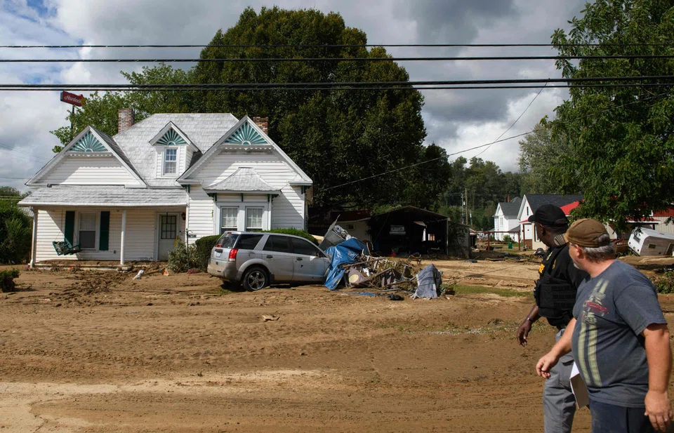 People walk through mud-filled streets in the aftermath of Hurricane Helene In Old Fort, North Carolina, Sept 29, 2024. 