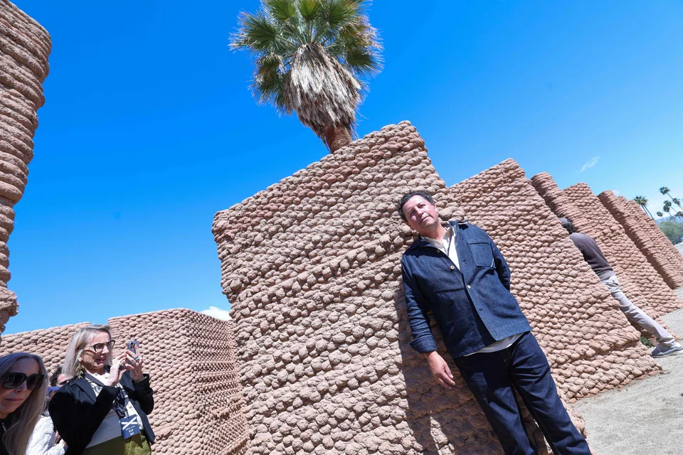 Artist Ronald Rael next to his piece “Adobe Oasis",  which used an enormous robotic arm to 3D-print walls made of clay and straw, in the adobe style traditional in this region.