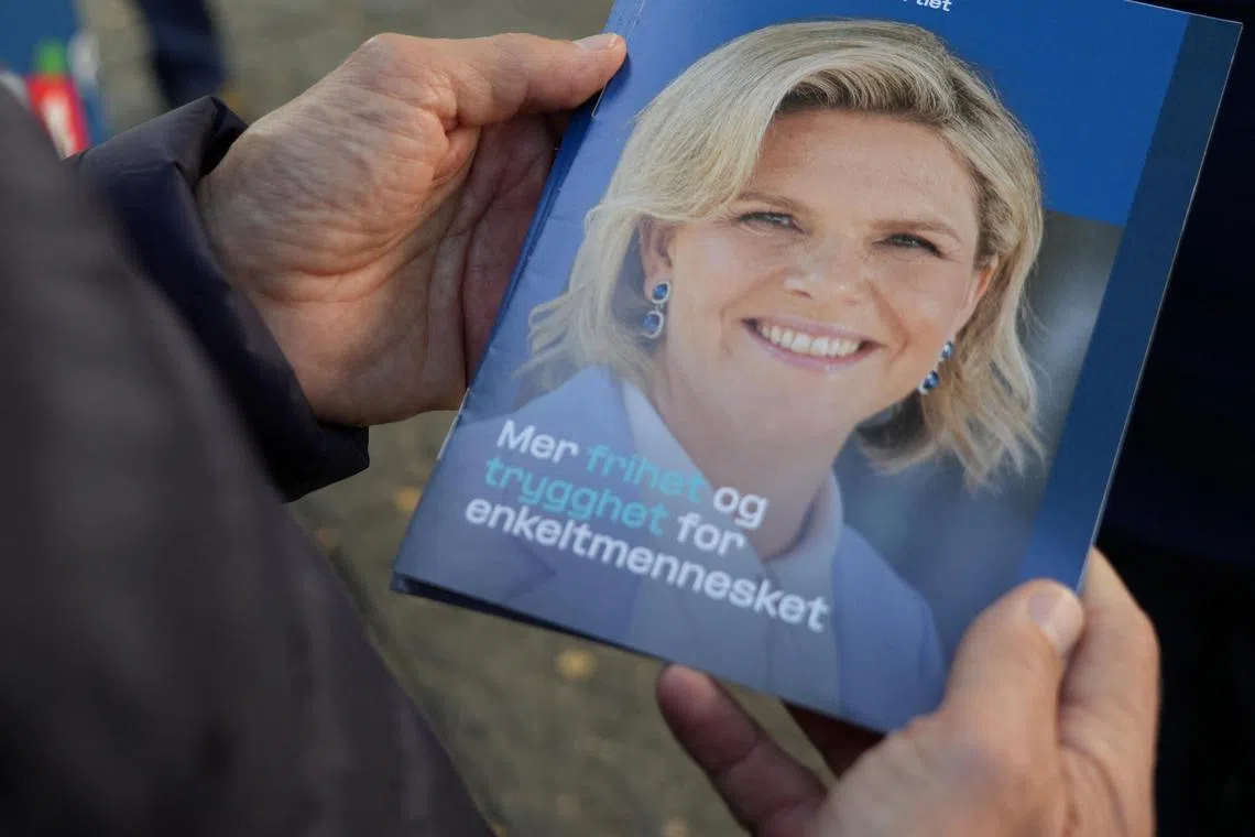 A supporter of the Progress Party holds a leaflet showing party leader Sylvi Listhaug, who says "Norway should be the last country in the world to stop (oil) production".