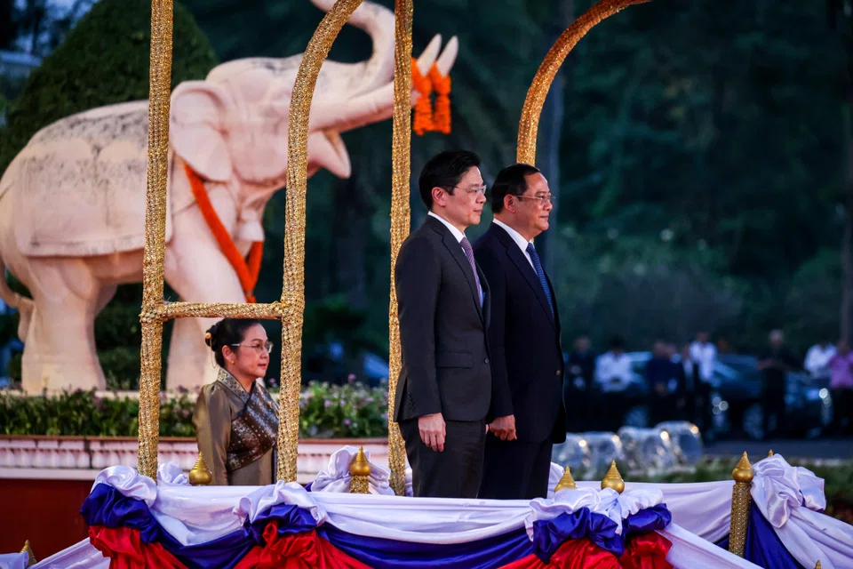 PM Wong with Lao PM Sonexay Siphandone at a welcome ceremony in Vientiane on Friday. Behind them is PM Sonexay's wife Vandara Siphandone.