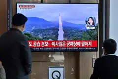 People watch a television screen showing a news broadcast with file footage of a North Korean missile test, at a railway station in Seoul on Nov 2, 2022. 