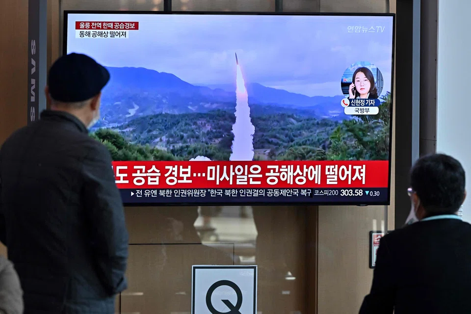 People watch a television screen showing a news broadcast with file footage of a North Korean missile test, at a railway station in Seoul on Nov 2, 2022. 