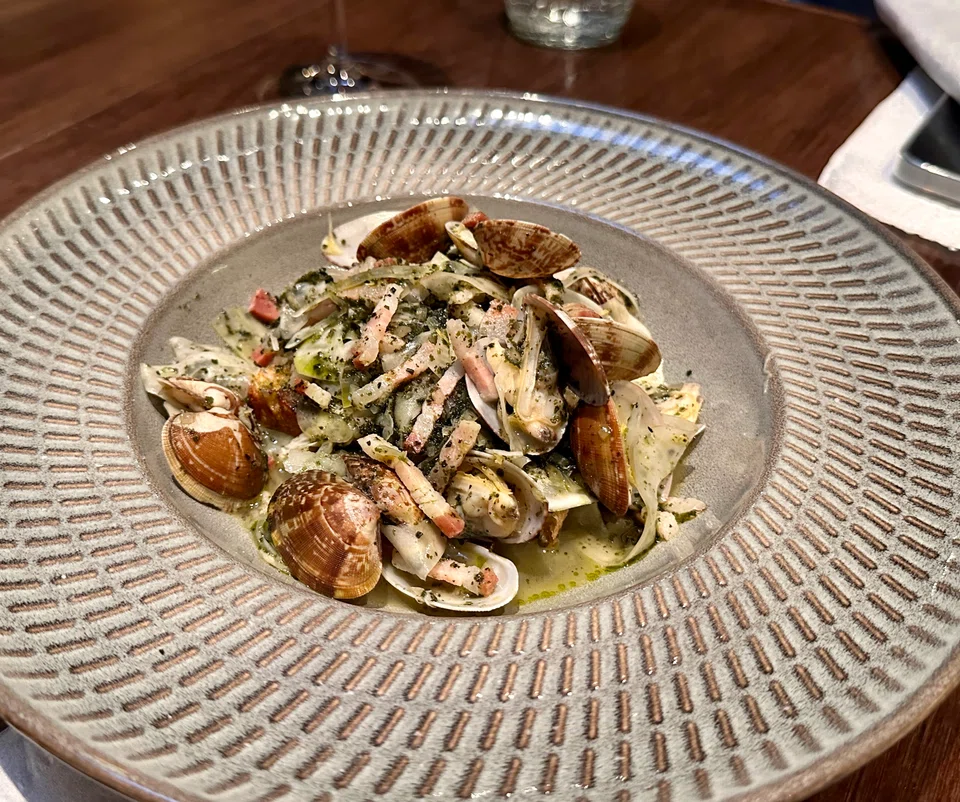 Clams bathed in broth with pancetta and fennel.