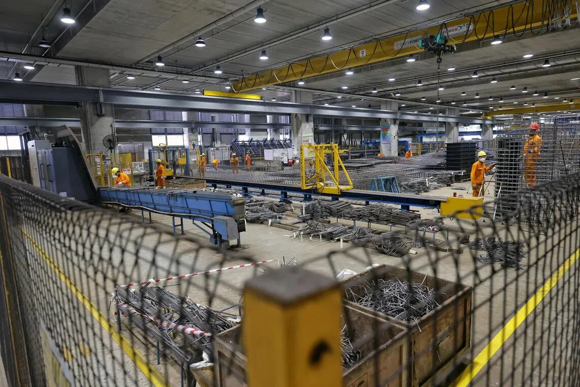 Workers assembling steel that has been cut to length into a cage-like structure, which serves as a reinforcement for precast components.