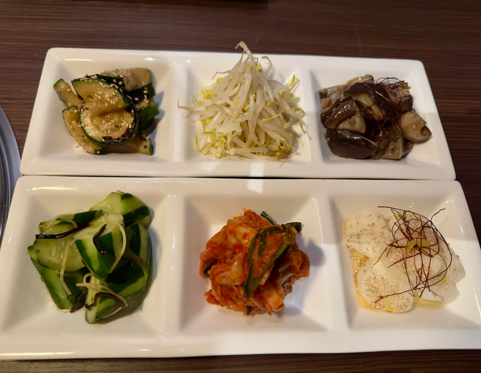 Assorted pickles and marinated vegetables counter the fattiness of the beef.