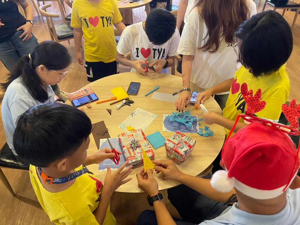 Touch Young Arrows beneficiaries making Christmas cards with volunteers at the festive celebration on Saturday at Coliwoo Boon Lay.