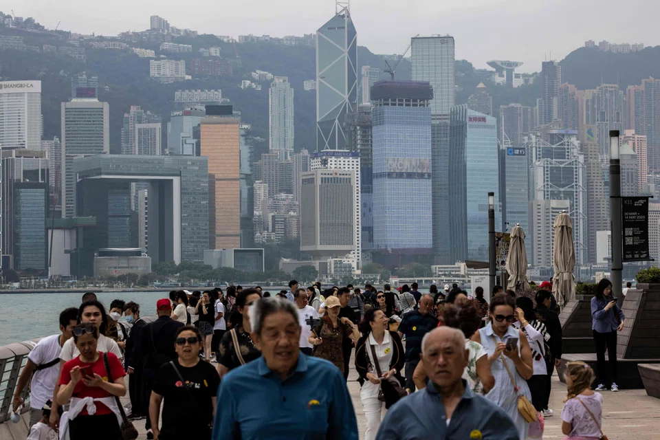 People walk along the promenade next to Victoria Harbour in Hong Kong. The city's tourism and hospitality sectors are thriving, four months after Hong Kong's borders were fully reopened. 