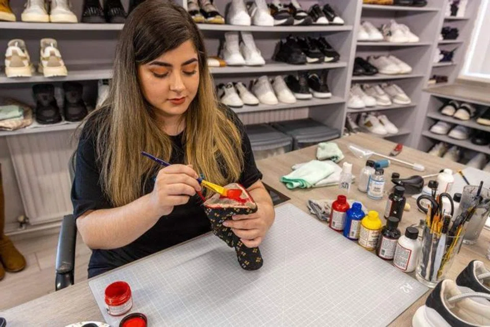 Andreia Pacheco repaints the sole on a shoe at Shoe Lab in Boston, UK. 