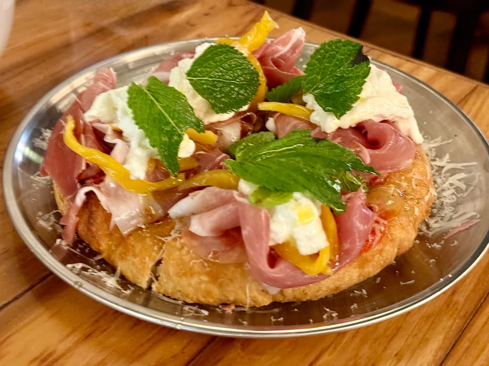 Fried and baked pizza round with parma ham and burrata cheese.