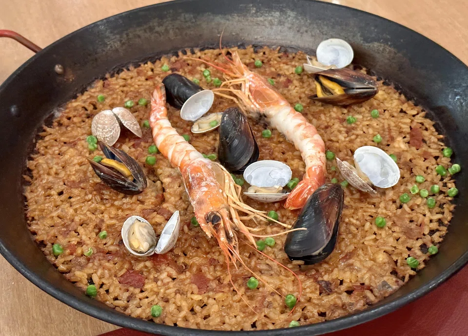 Seafood paella features scorched tomato-based rice.