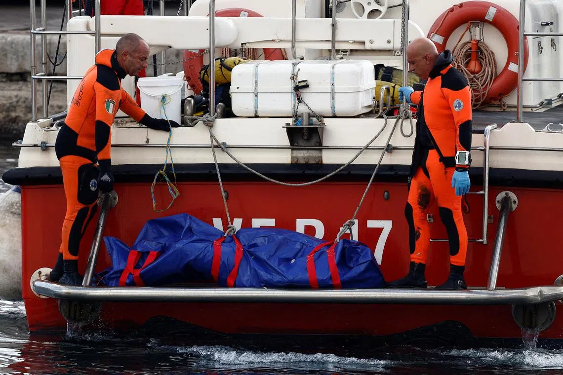 Rescue personnel stand near the body of a person in a bodybag at the scene where a luxury yacht sank, off the coast of Porticello, near the Sicilian city of Palermo, Italy.