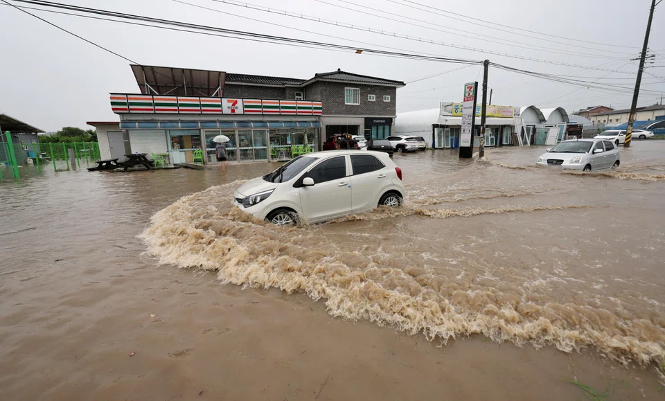 A vehicle makes its way through a flooded area caused by heavy rain in Cheongju, South Korea. 