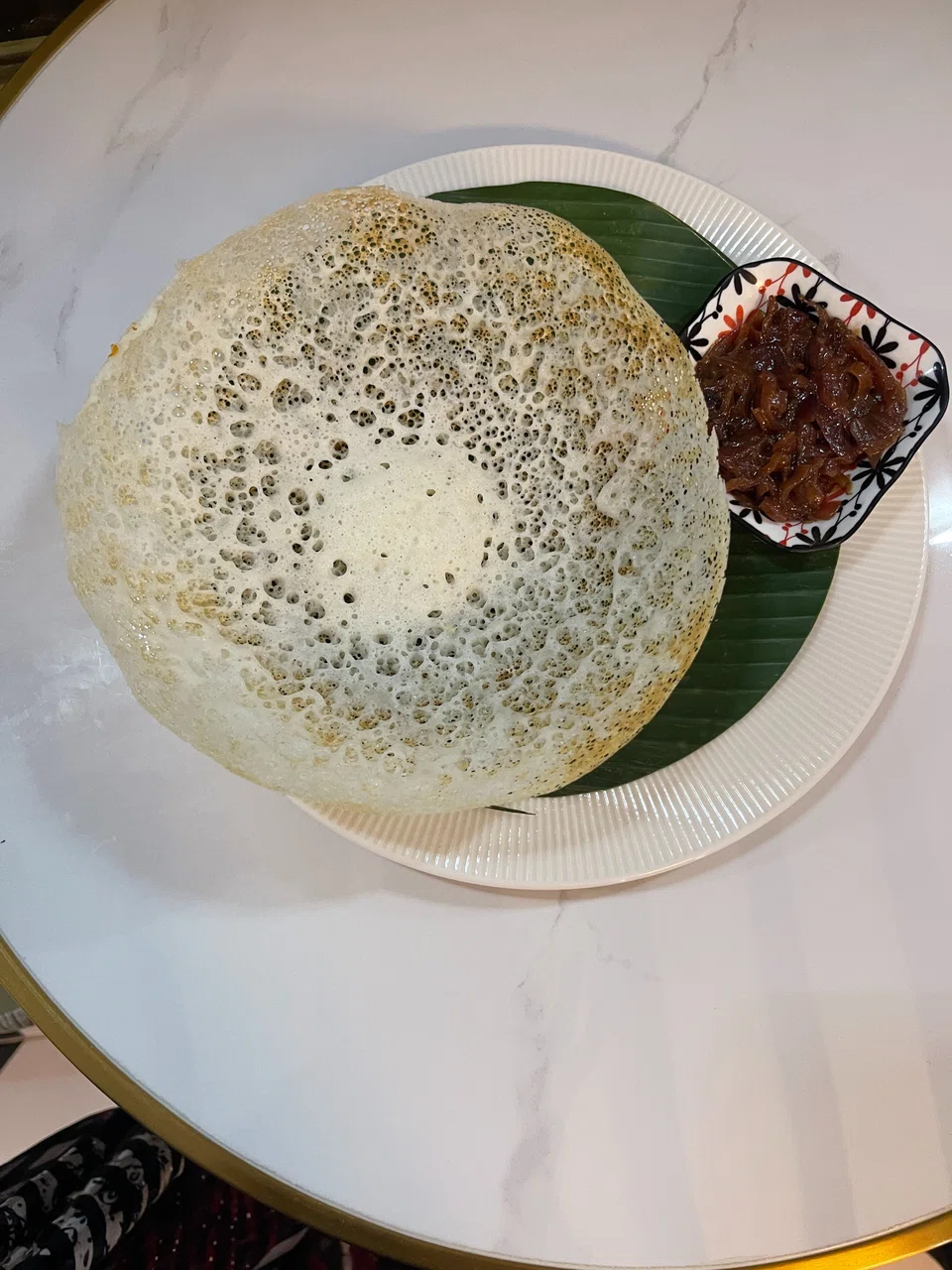 Light, tangy appam is served with caramelised onions.