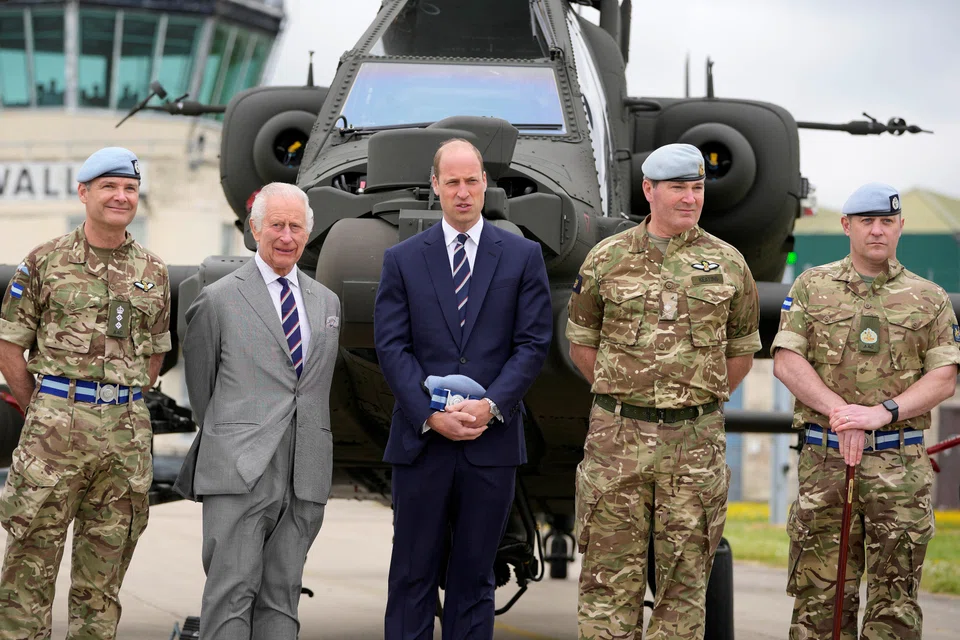 Britain's King Charles III poses with service personnel after he officially handed over the role of Colonel-in-Chief of the Army Air Corps to Prince William, Prince of Wales.
