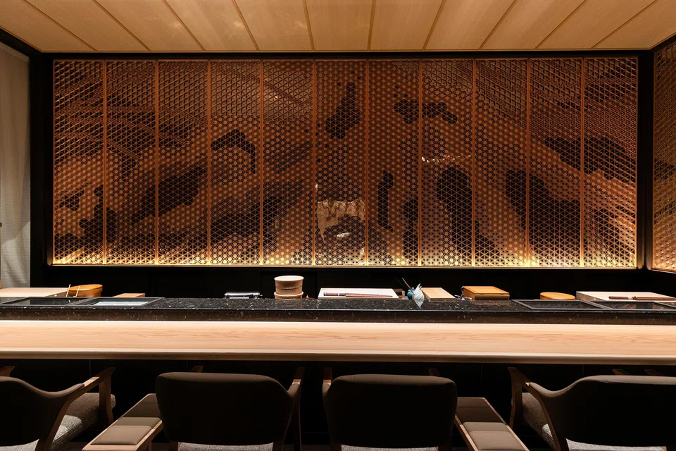 Intricate wooden panels adorn the wall behind Aoki's sushi counter.