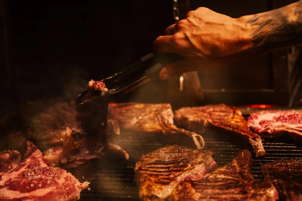 A grill master, or “parrillero”, preparing T-bone steaks at Rincon Escondido, a restaurant in Sao Paolo, Brazil. 
