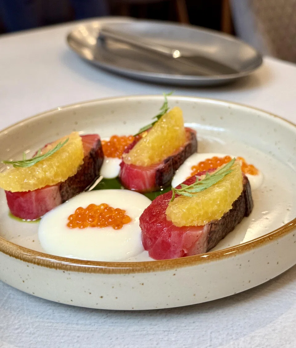 Cured salmon slices topped with orange segments.