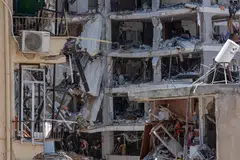Israeli rescue teams combing through the rubble of residential buildings destroyed in strikes, using flashlights and sniffer dogs to look for survivors.
