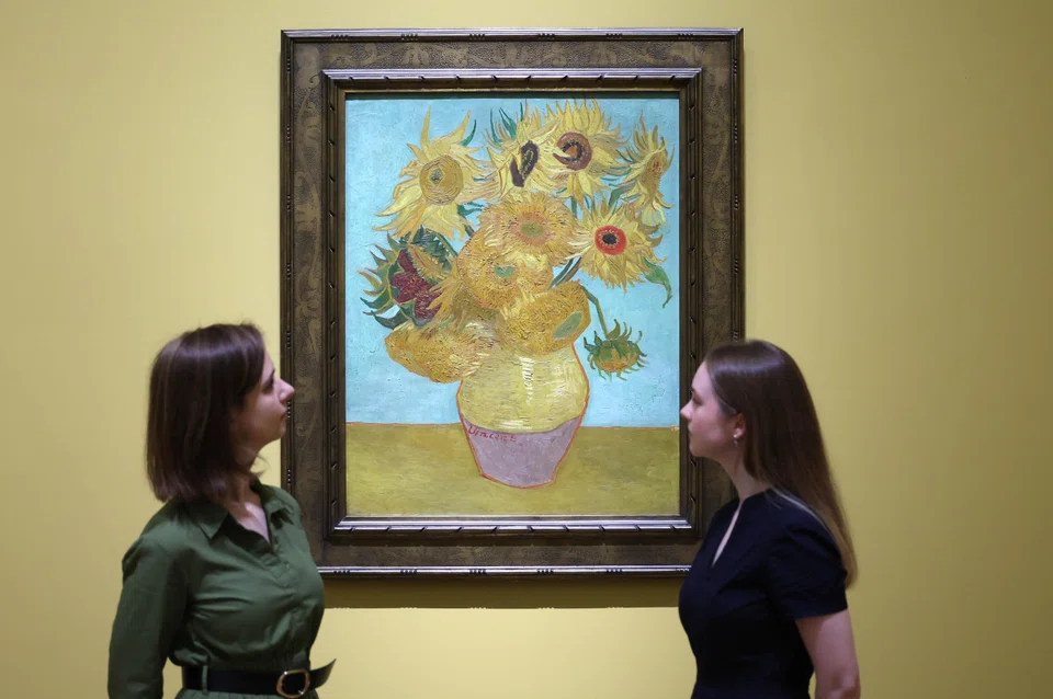 Gallery workers view Dutch artist Vincent van Gogh's work titled 'Sunflowers' (1889) during a preview for the exhibition 'Van Gogh: Poets and Lovers' at the National Gallery in London.