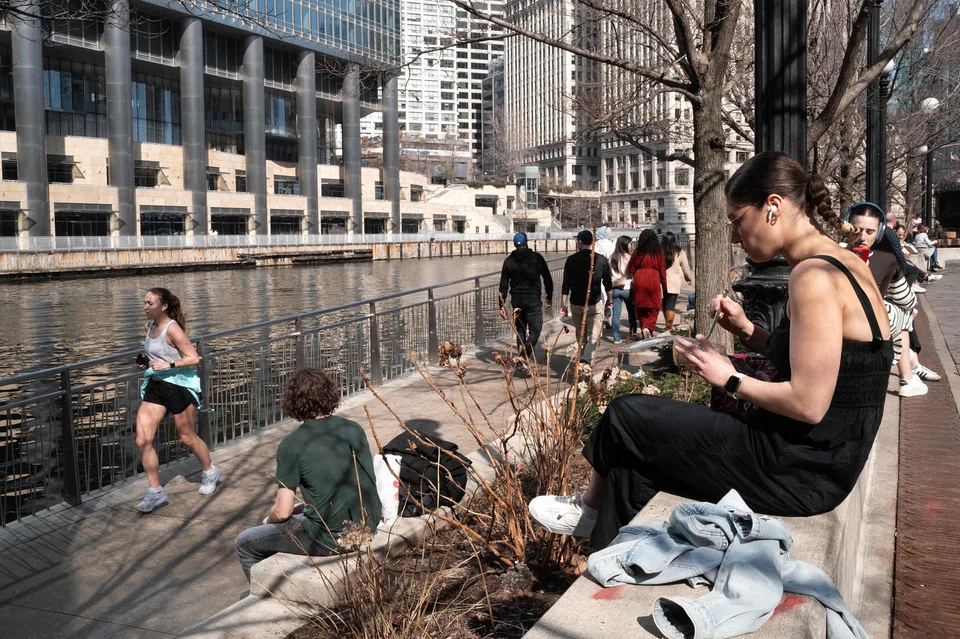 People at the downtown Riverwalk in Chicago during an unusually warm winter day on Feb 27. The city was then hit with severe thunderstorms that night, bringing hail and reported tornadoes. 