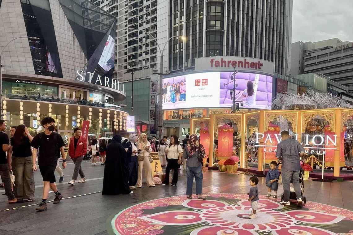 A bustling pedestrian area at Bukit Bintang, featuring major shopping destinations including Pavilion Kuala Lumpur, Fahrenheit88, and The Starhill. Located in the heart of Kuala Lumpur's retail district, this area is a famous tourist spot known for its vibrant street scene, modern architecture, and large advertising screens. The area frequently features festive decorations and large-scale art installations in the pedestrian plaza.