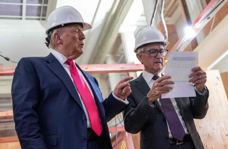US President Donald Trump points to a cost sheet as he speaks with Federal Reserve chair Jerome Powell (right) as he visits the Federal Reserve in Washington, D.C., July 24, 2025. 