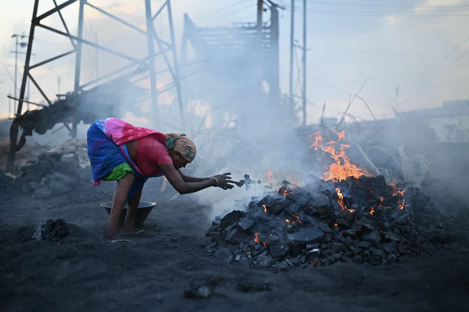 A coal picker burns raw coal at an open-cast mine in Jharia on the outskirts of Dhanbad in India's Jharkhand state on May 24, 2024. 