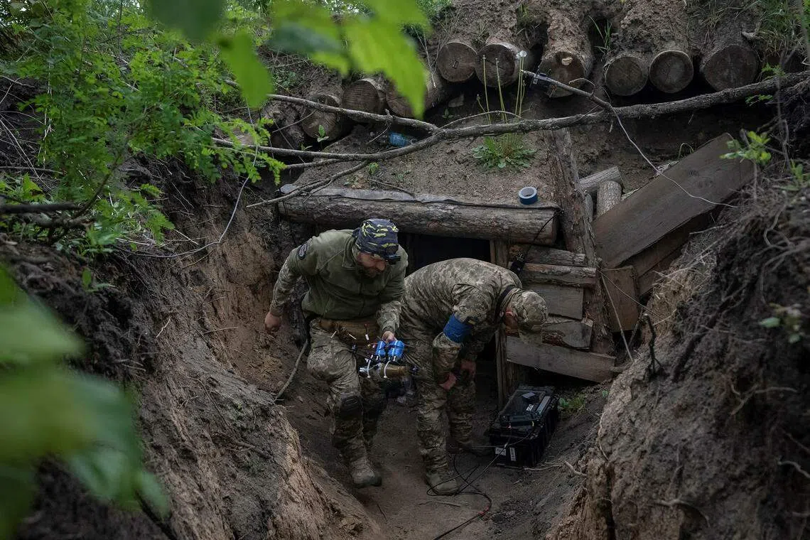 A Ukrainian serviceman of the attack drones battalion of the Achilles, 92nd brigade carries a first-person view (FPV) drone before it flies, near a Russian border in a Kharkiv region, Ukraine May 15, 2024. REUTERS/Inna Varenytsia