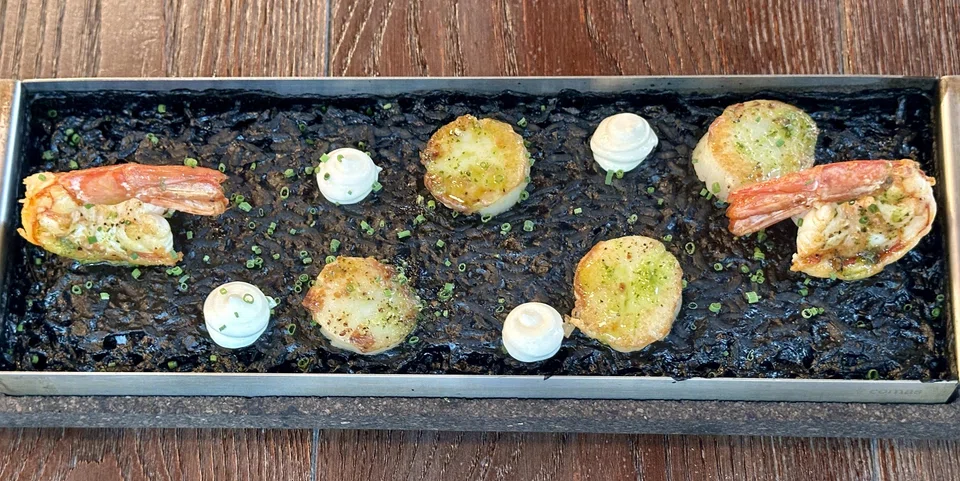 Squid ink paella topped with prawns and scallops.