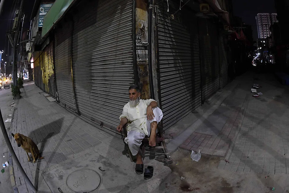 A man sits outside a closed shop on Apr 10 at a market after authorities ordered closures to reduce energy consumption in Karachi.