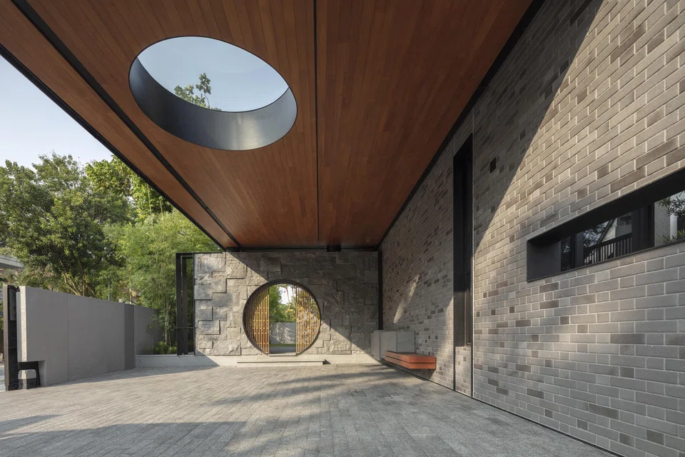 In the car porch, an oculus skylight echoes the shape of the moon gate, while grey brick and rough granite walls bring to mind classical Chinese building styles. 