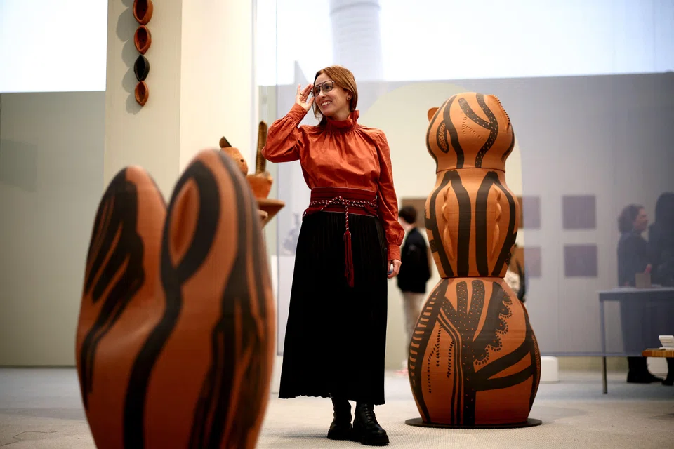 Venezuelan artist Lucia Pizzani poses beside a ceramic artwork displayed as part of her exhibition "Smoke" during the Frieze Art Fair at Regent's Park in London.