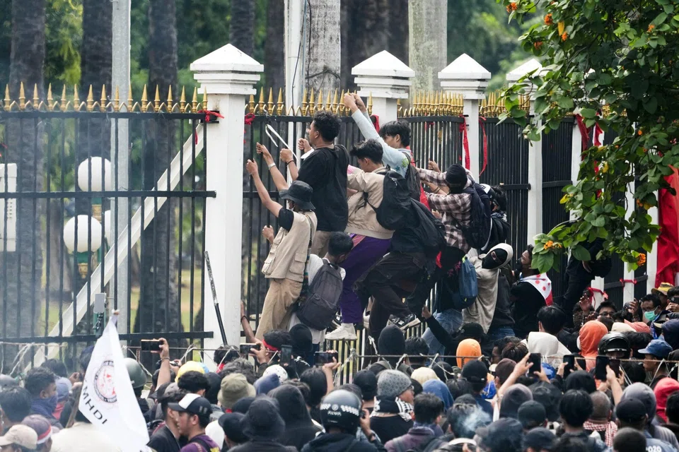Protesters climbing a fence outside the Parliament complex in Jakarta, on Thursday (Aug 22).  