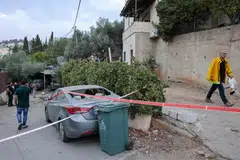 A man walks past a car hit by rockets fired from Gaza in the Arab-Israeli town of Abu Ghosh near Jerusalem on Monday. 