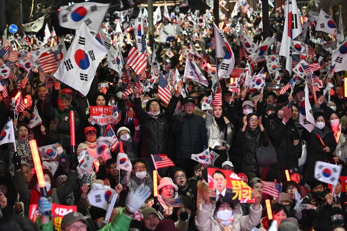 Supporters of impeached South Korean President Yoon Suk Yeol wave South Korean and US flags during a rally near the presidential residence in Seoul on March 8, 2025 after a motorcade carrying Yoon arrived at the residence. 