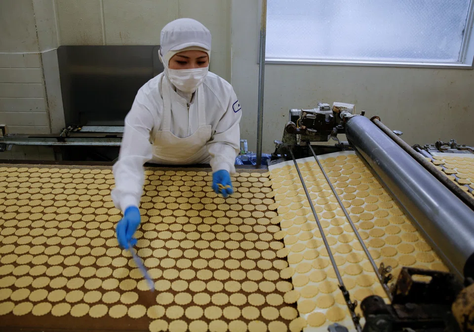 An employee inspects cookies at Izumiya Tokyoten's factory in Kawasaki, south of Tokyo, Japan, July 9, 2024. When Yukiko Izumi took over her family’s cookie company after her father died six years ago, it had lost money for a decade.