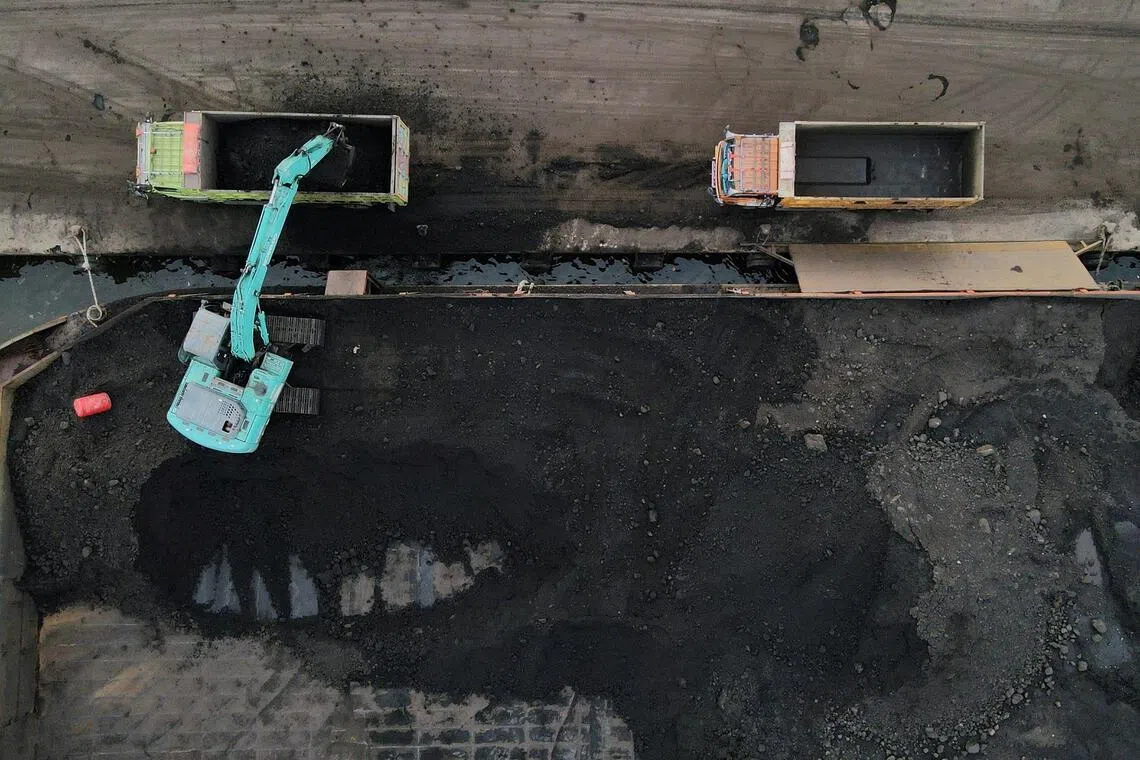 FILE PHOTO: A heavy machinery unload coal from barges into trucks to be distributed, at the Karya Citra Nusantara port in North Jakarta, Indonesia, January 13, 2022. Picture taken with a drone. REUTERS/Willy Kurniawan/File Photo
