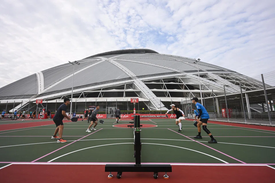 Pickleball players enjoying a match at the newly opened dual-use courts at The Kallang, with the National Stadium in the background.