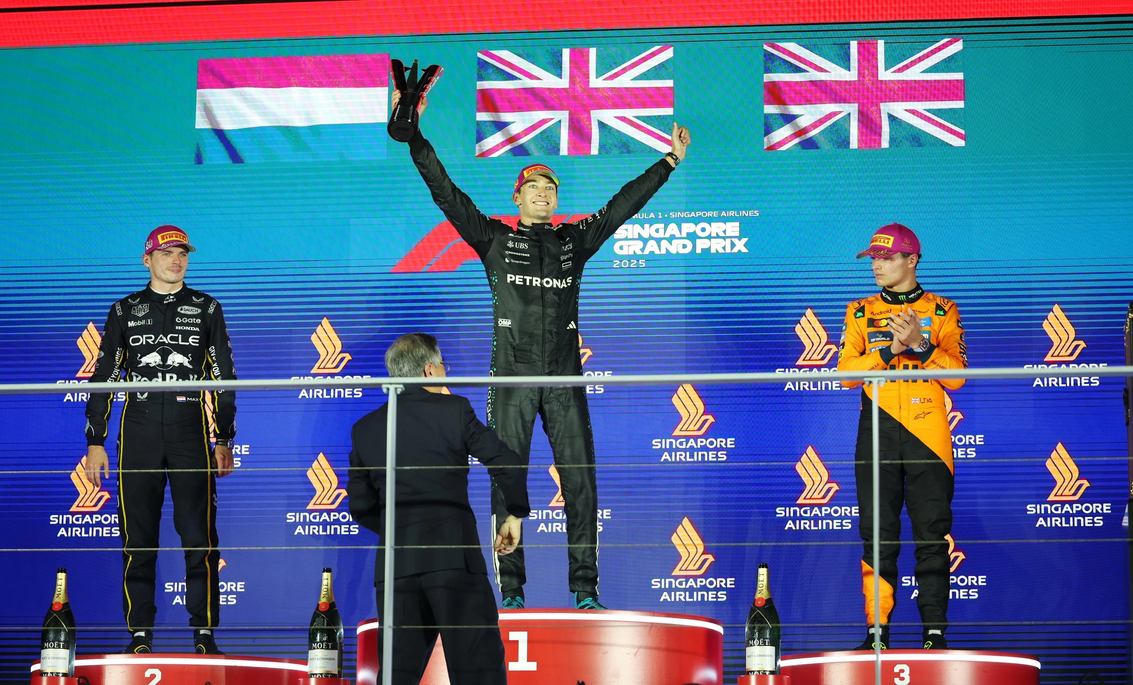 Race winner Mercedes driver George Russell (center) Max Verstappen (left), second-placed Red Bull racing driver from England and Netherlands, and Landnoris, the third McLaren driver from England to celebrate after the race.