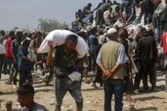 A man carries a bag of food as displaced Palestinians raid trucks carrying humanitarian aid in Khan Yunis, in the southern Gaza Strip.
