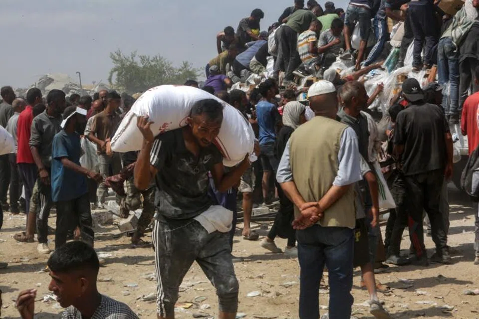 A man carries a bag of food as displaced Palestinians raid trucks carrying humanitarian aid in Khan Yunis, in the southern Gaza Strip.