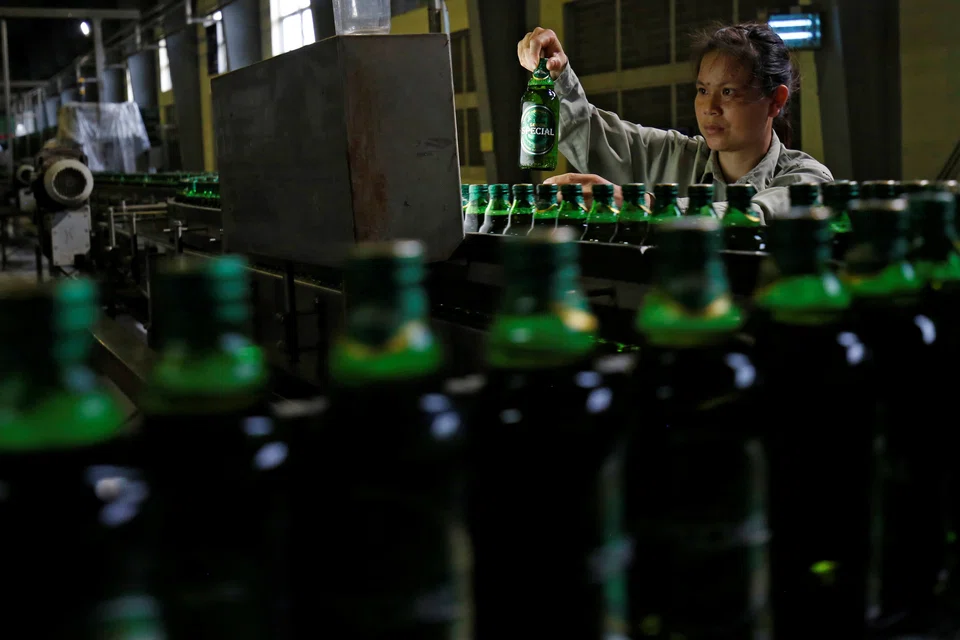 A worker doing checks on beer bottles along a production line in a Saigon Beer Corporation (Sabeco) factory in Hanoi, Vietnam, June 2017.