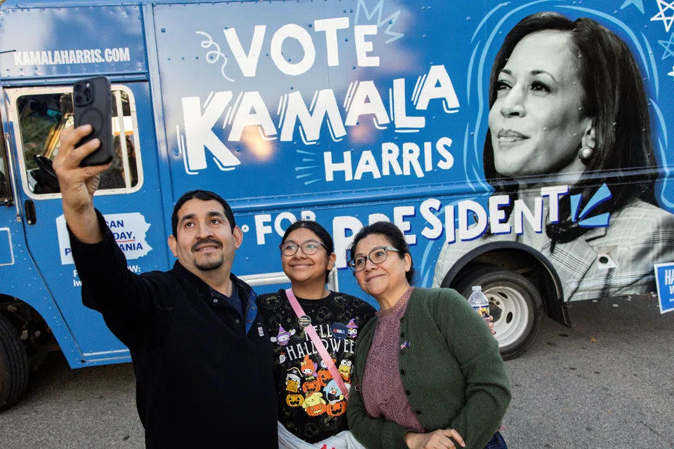 Supporters of Democratic presidential nominee US Vice-President Kamala Harris take a selfie beside a truck distributing merchandise in support of Harris, Philadelphia, Pennsylvania, Oct 27, 2024.