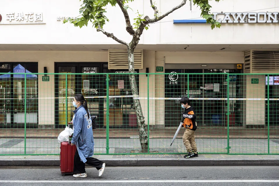 Residents pass fenced off buildings at a neighborhood in Shanghai, China, on Tuesday, May 3, 2022. 