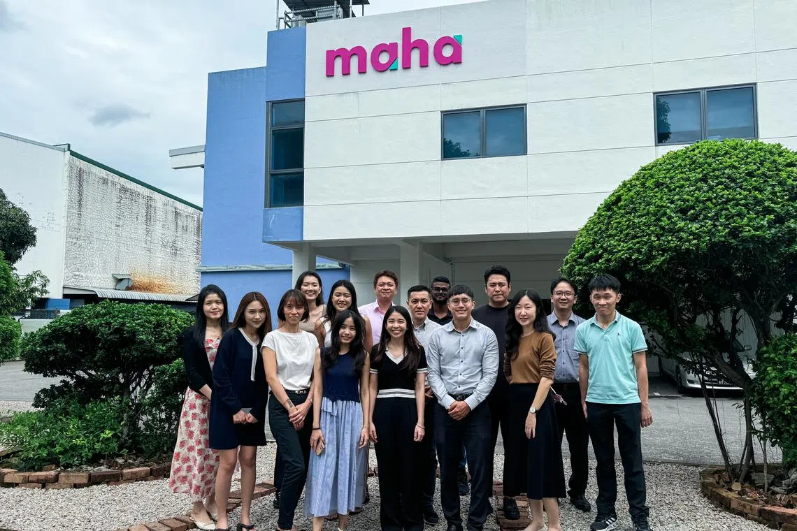 Managing director Chew Chin Seong (second row, centre) with Maha Asia's team in front of a warehouse bearing the company's new logo.
