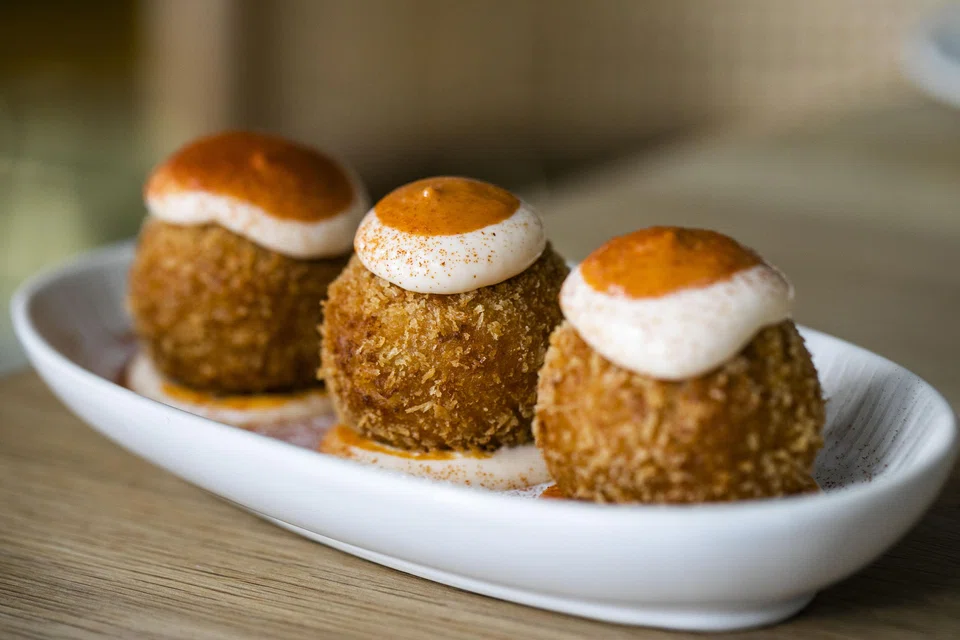 Bombas of crispy meatballs slathered in aioli and harissa sauce.