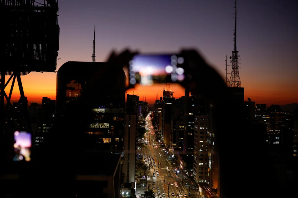 Visitors take photographs at the Mirante do Sesc Avenida Paulista viewpoint in Sao Paulo, Brazil. High mobile penetration rates in South America present opportunities for Singapore companies.