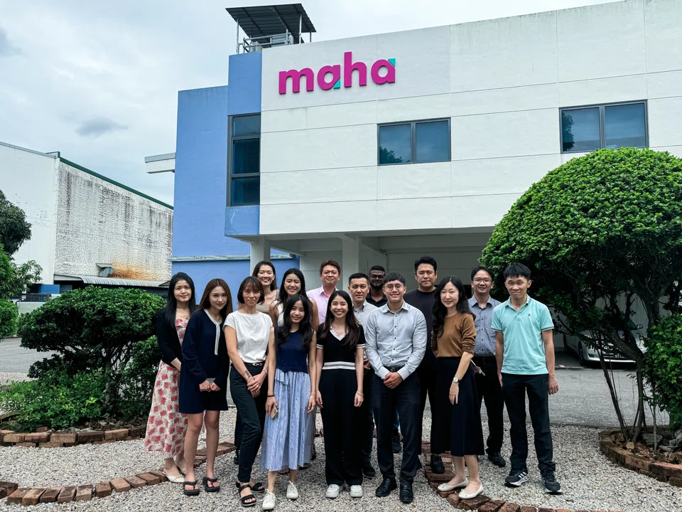 Managing director Chew Chin Seong (second row, centre) with Maha Asia's team in front of a warehouse bearing the company's new logo.